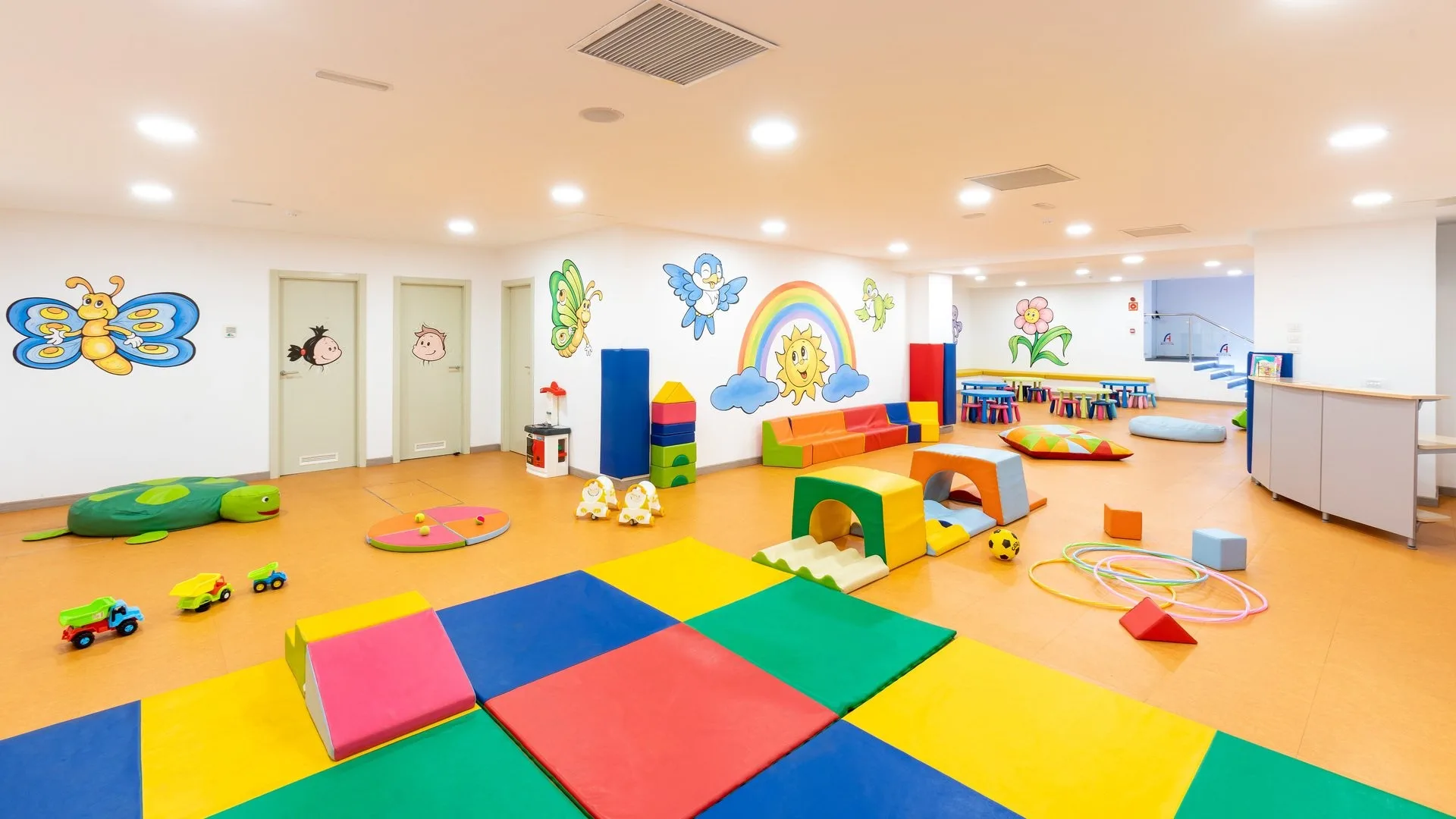 Sala giochi per bambini colorata con tappeti morbidi e decorazioni alle pareti