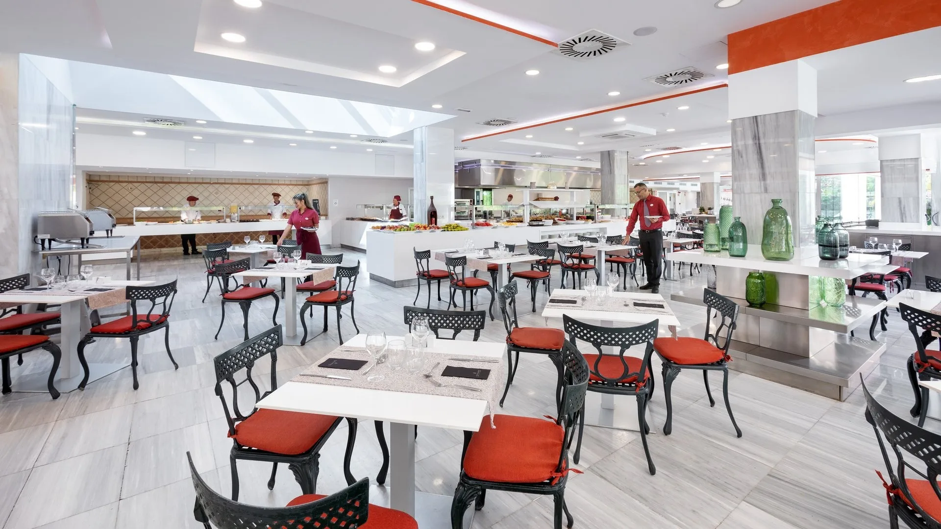 Sala ristorante moderna con tavoli apparecchiati, sedie rosse e zona buffet