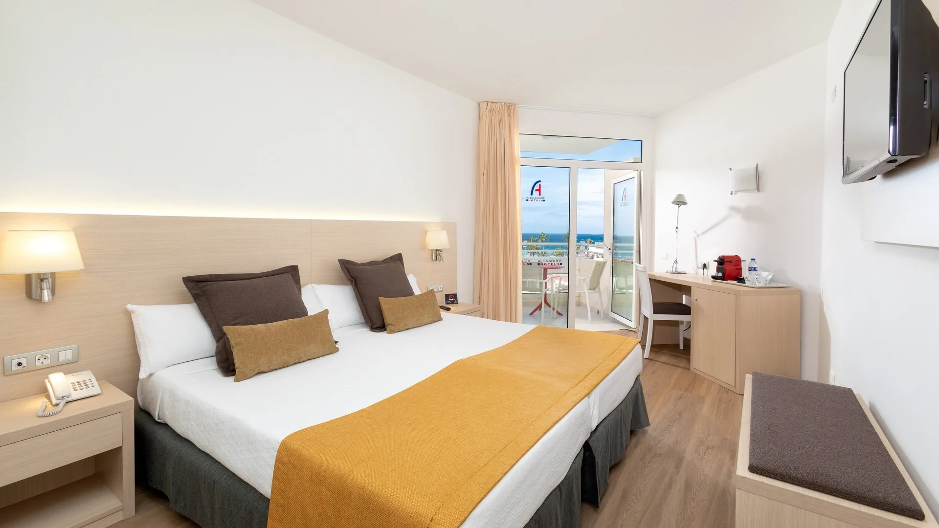 Camera con letto matrimoniale, dettagli in tonalità calde e balcone vista mare