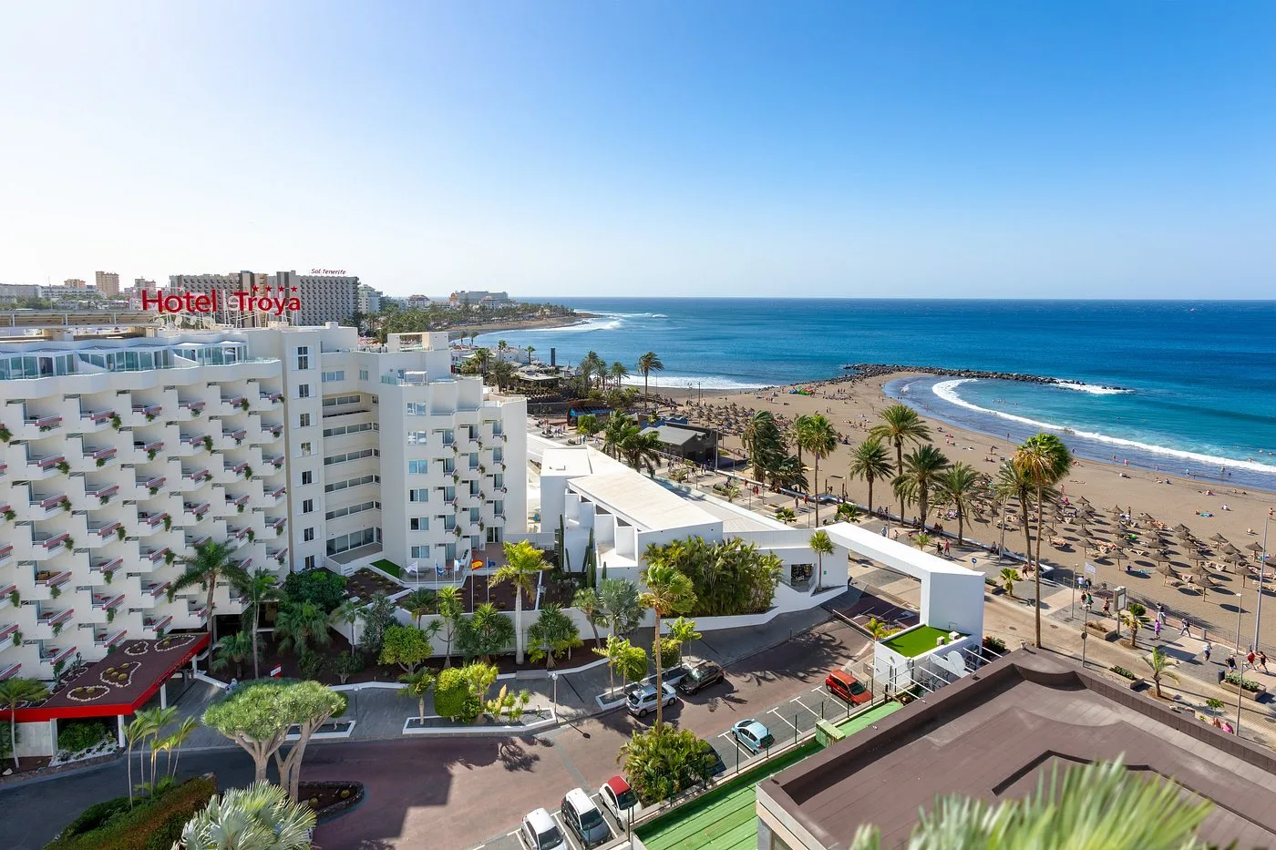 Veduta aerea dell'Hotel Troya con spiaggia, palme e mare sullo sfondo