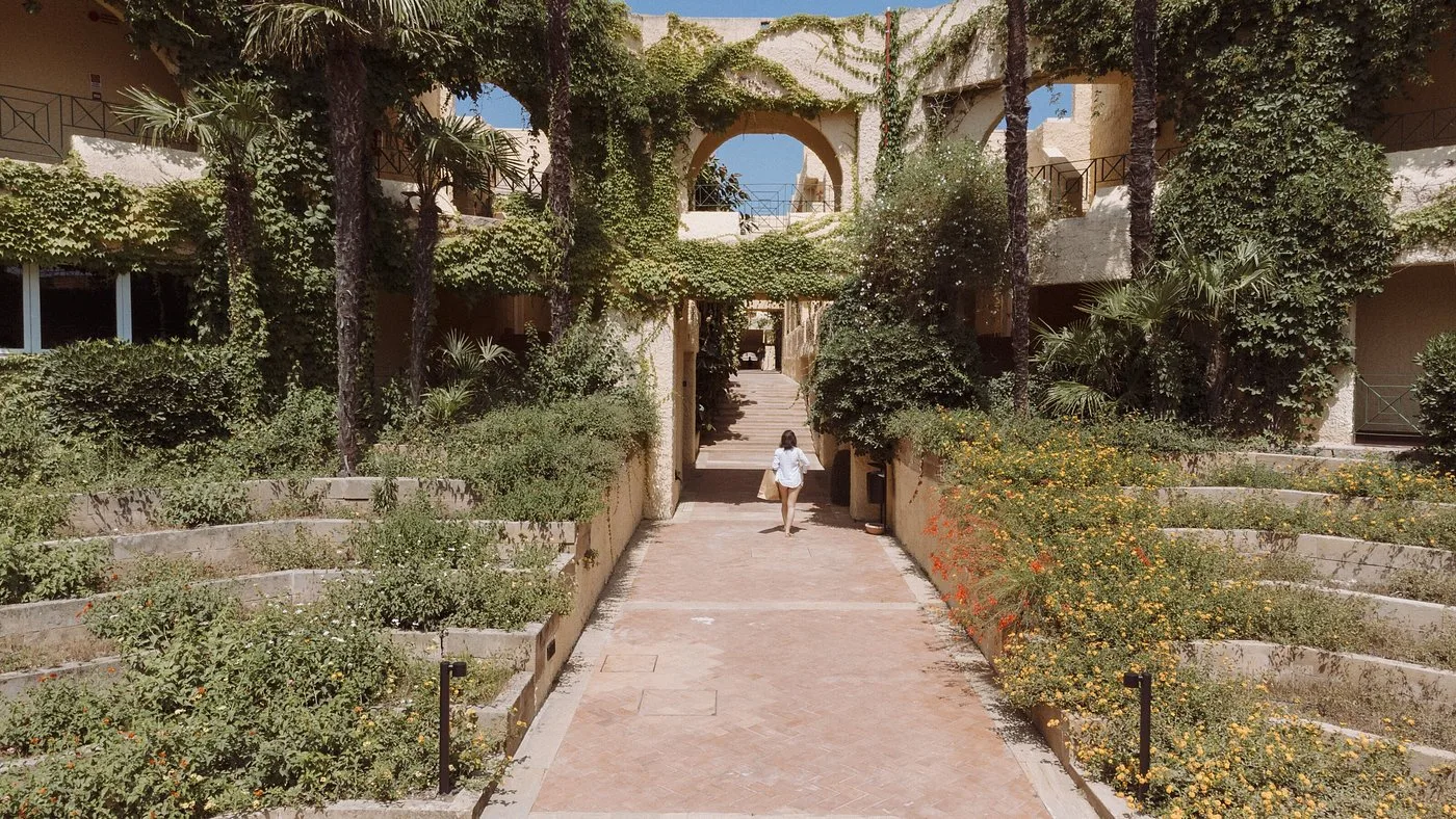 Cortile del resort con vegetazione rigogliosa e archi in pietra
