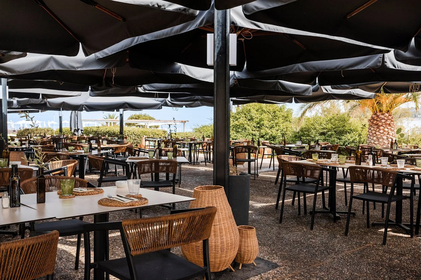 Ristorante all'aperto con tavoli, sedie in rattan e ombrelloni
