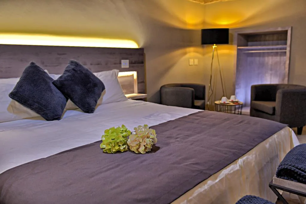 Camera elegante con letto king size, cuscini blu e poltrone, illuminazione soffusa