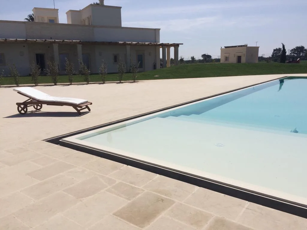 Piscina esterna con lettino e vista sulla masseria in pietra chiara
