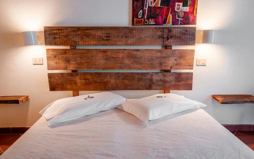 Testiera del letto in legno recuperato con cuscini bianchi e applique laterali