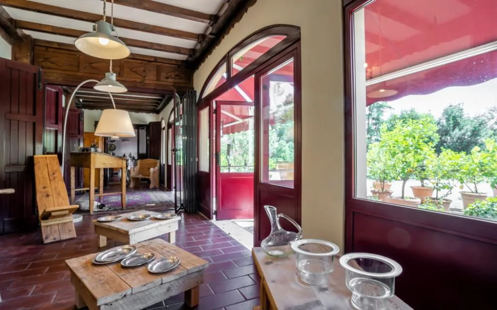 Veranda con soffitto in travi di legno, porte rosse e vista sul giardino con agrumi