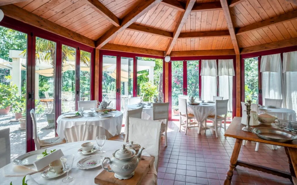 Sala colazione a vetrate con soffitto in legno a cupola e tavoli apparecchiati