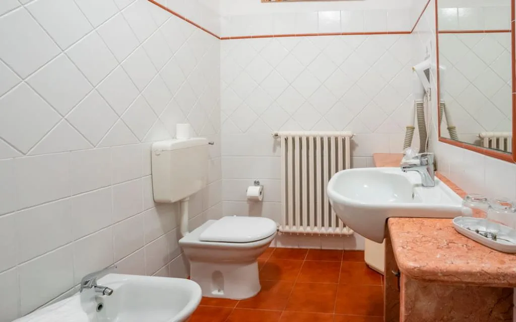 Bagno con pavimento in cotto, WC, bidet, lavabo e termosifone