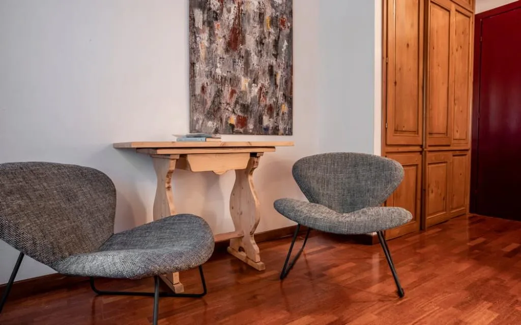 Angolo relax con poltrone grigie, tavolino in legno e dipinto astratto