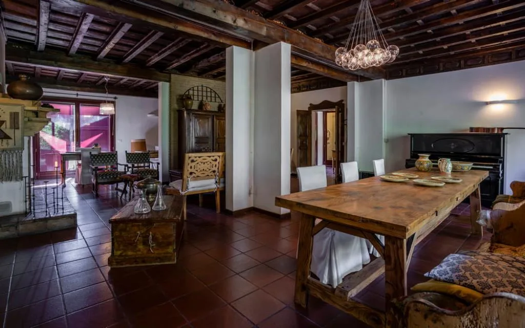 Ampio salone rustico con soffitto in legno, tavolo da pranzo e pianoforte