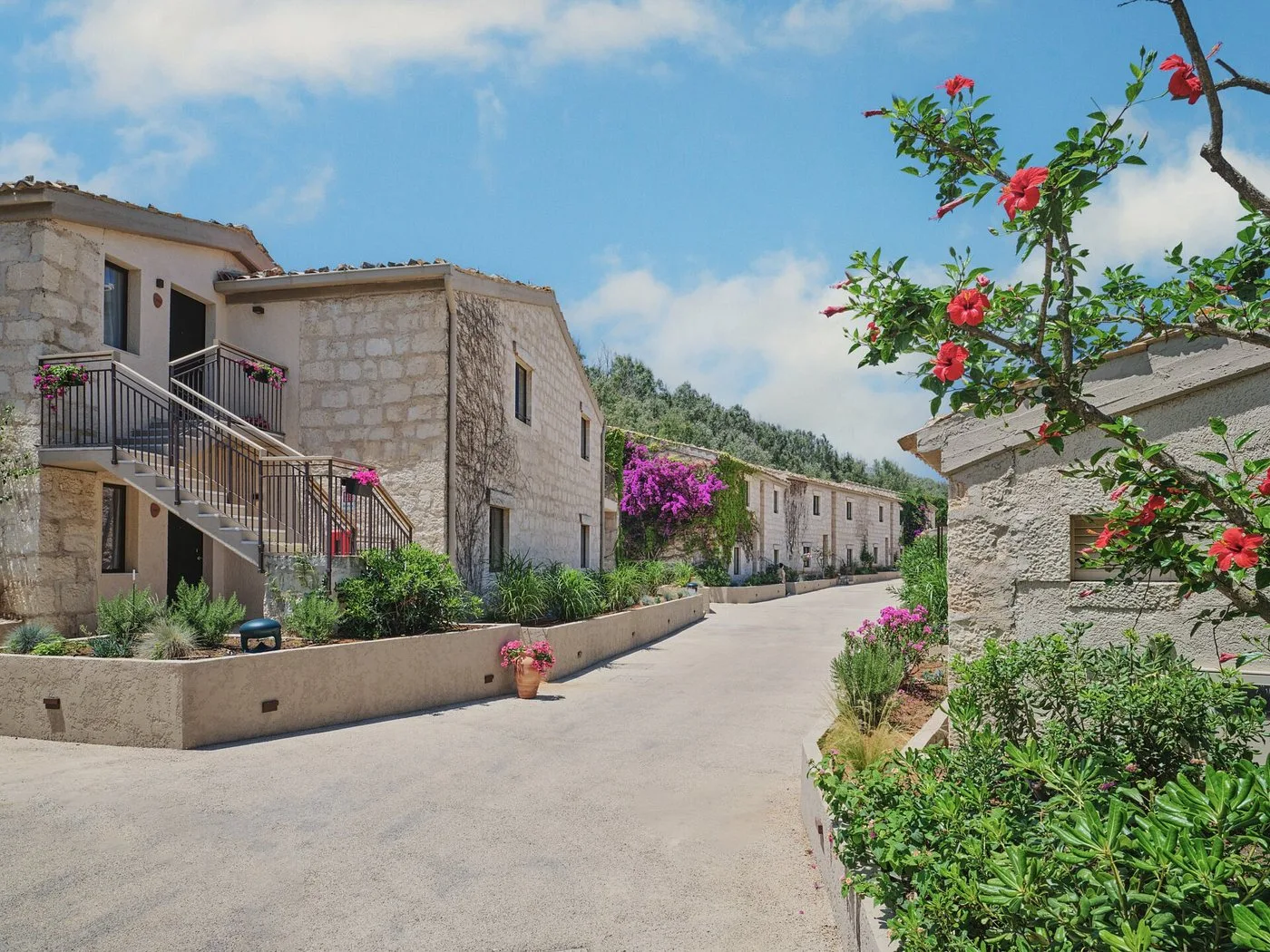 Strada interna del resort con edifici in pietra, scale esterne e fiori colorati