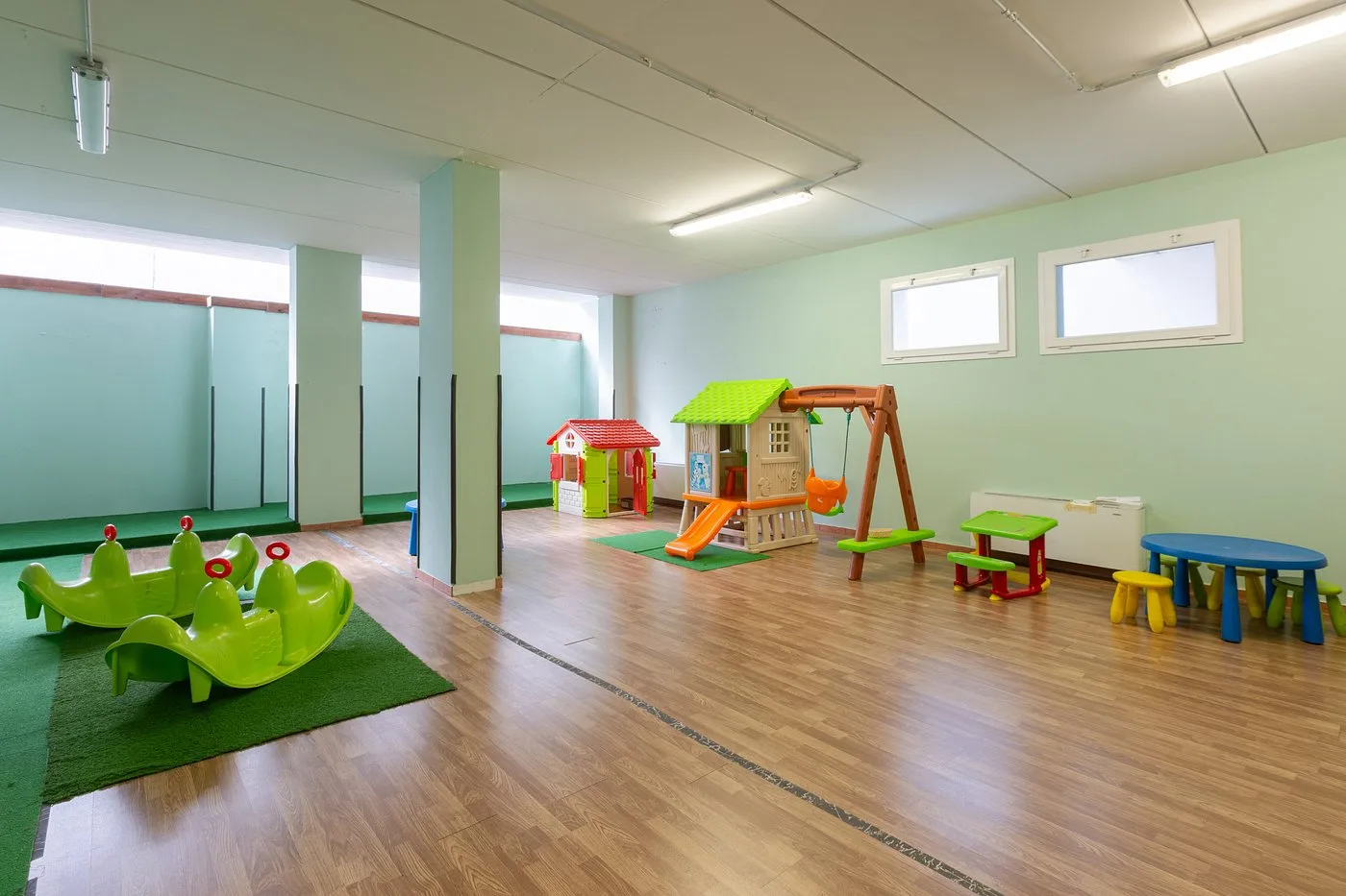 Sala giochi per bambini con giochi colorati, scivolo, altalena e tavolini