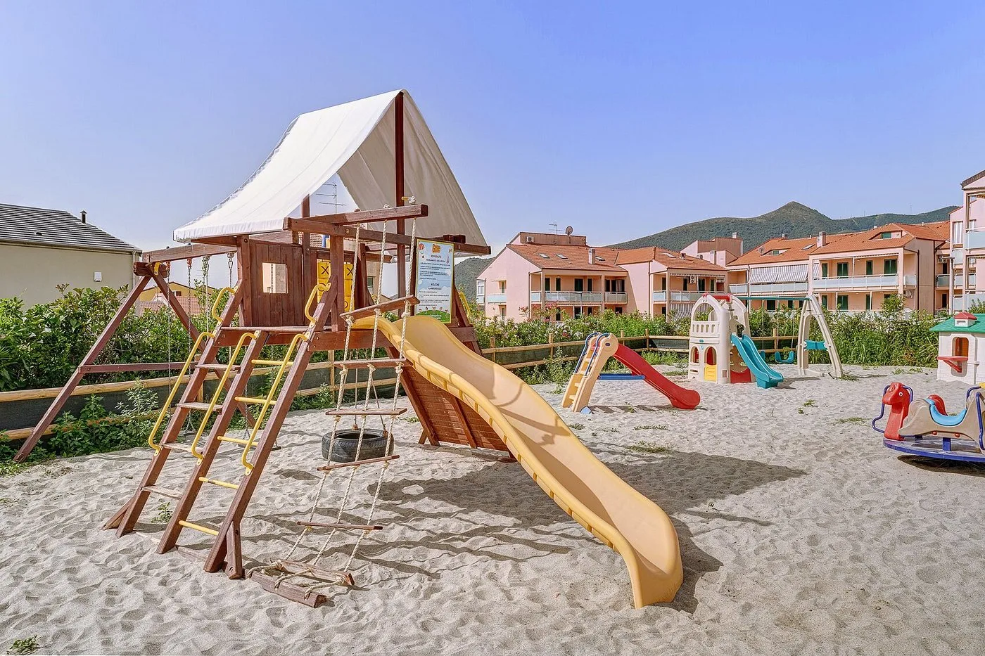 Parco giochi all'aperto per bambini con scivolo, altalena e giochi su sabbia
