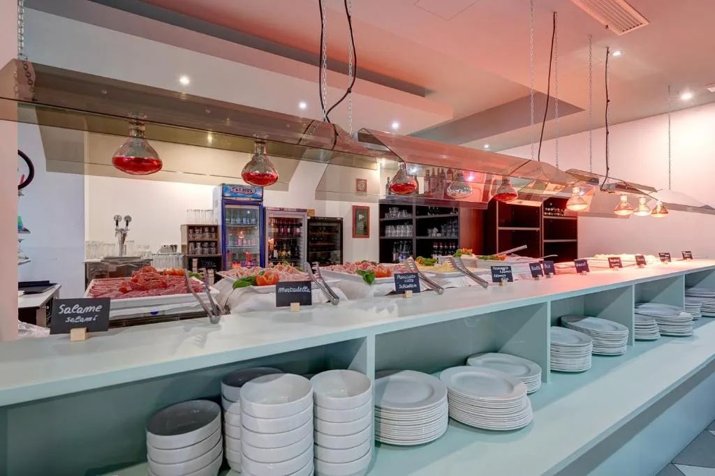 Buffet di salumi e formaggi con lampade riscaldanti e stoviglie impilate