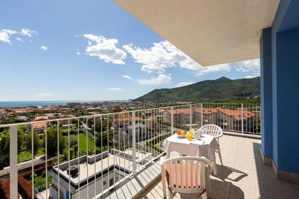 Balcone con tavolo apparecchiato per la colazione e vista panoramica su mare e montagne
