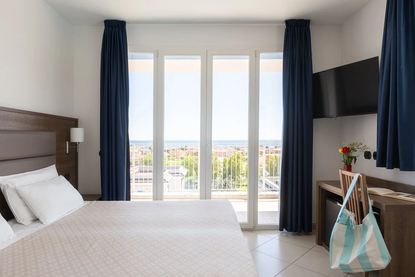 Camera matrimoniale con ampie vetrate, TV e vista sul mare in lontananza