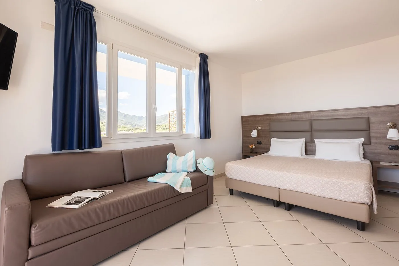 Camera spaziosa con letto matrimoniale, divano e finestre con vista sulle montagne