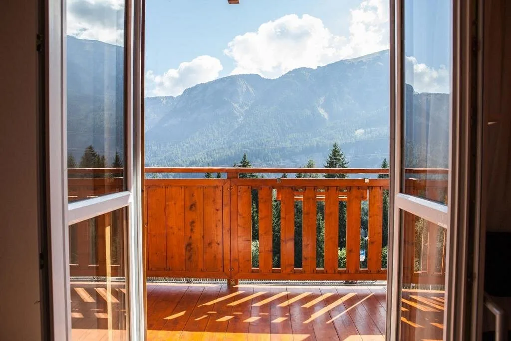 Vista sulle montagne e sui boschi dal balcone in legno della camera