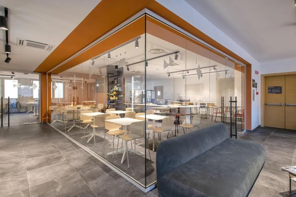 Area lounge con divano e sala ristorante separata da pareti in vetro