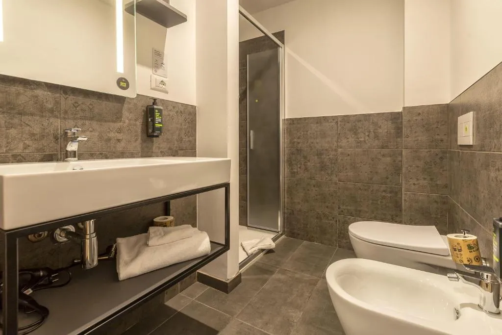 Bagno moderno con lavabo, doccia, WC e bidet e piastrelle grigie