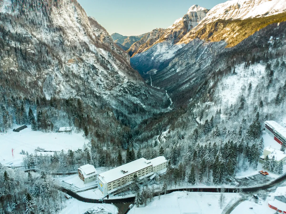 Veduta aerea dell'hotel nella valle alpina circondato da boschi innevati