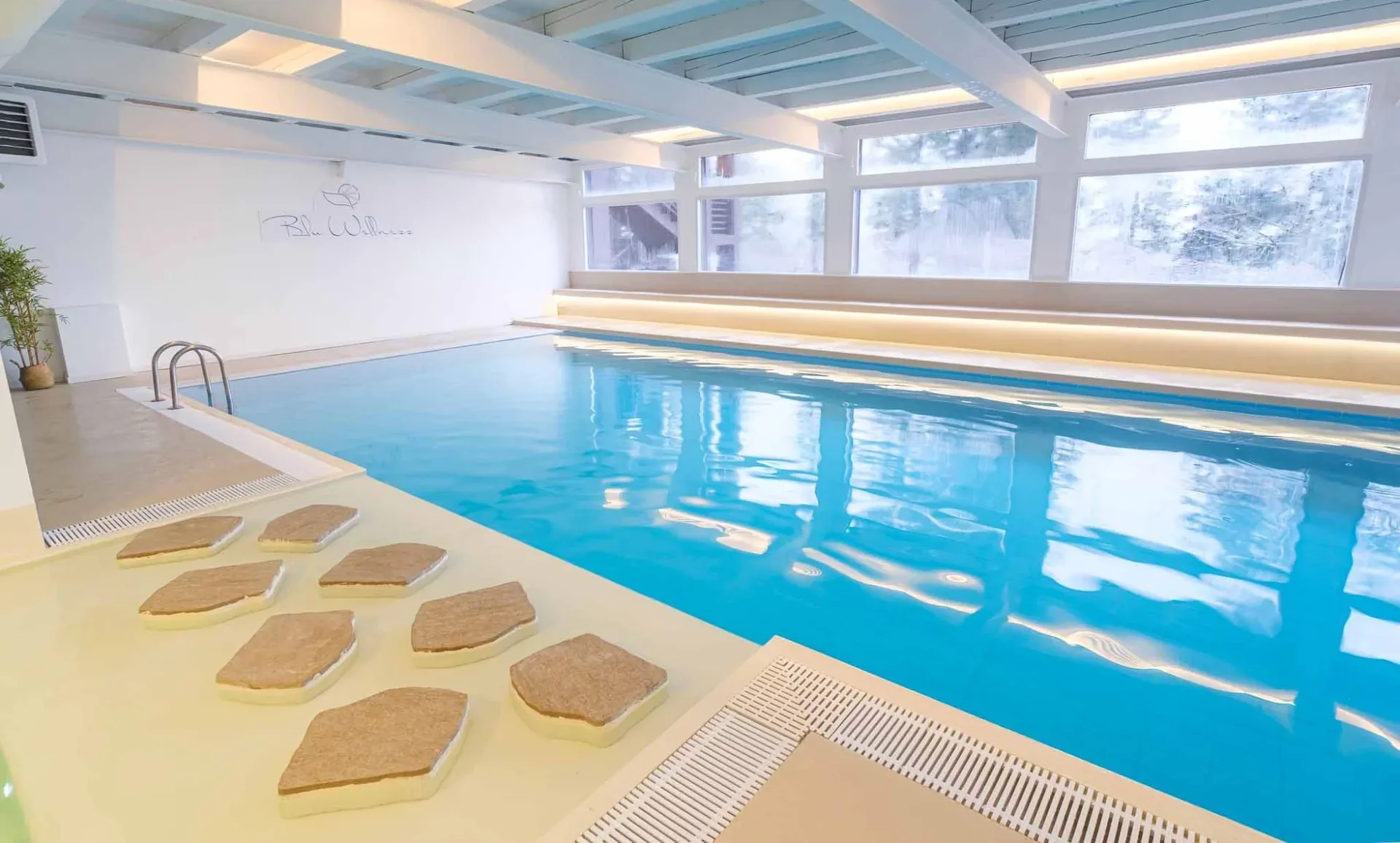 Piscina coperta Blu Wellness con lettini e grandi finestre luminose