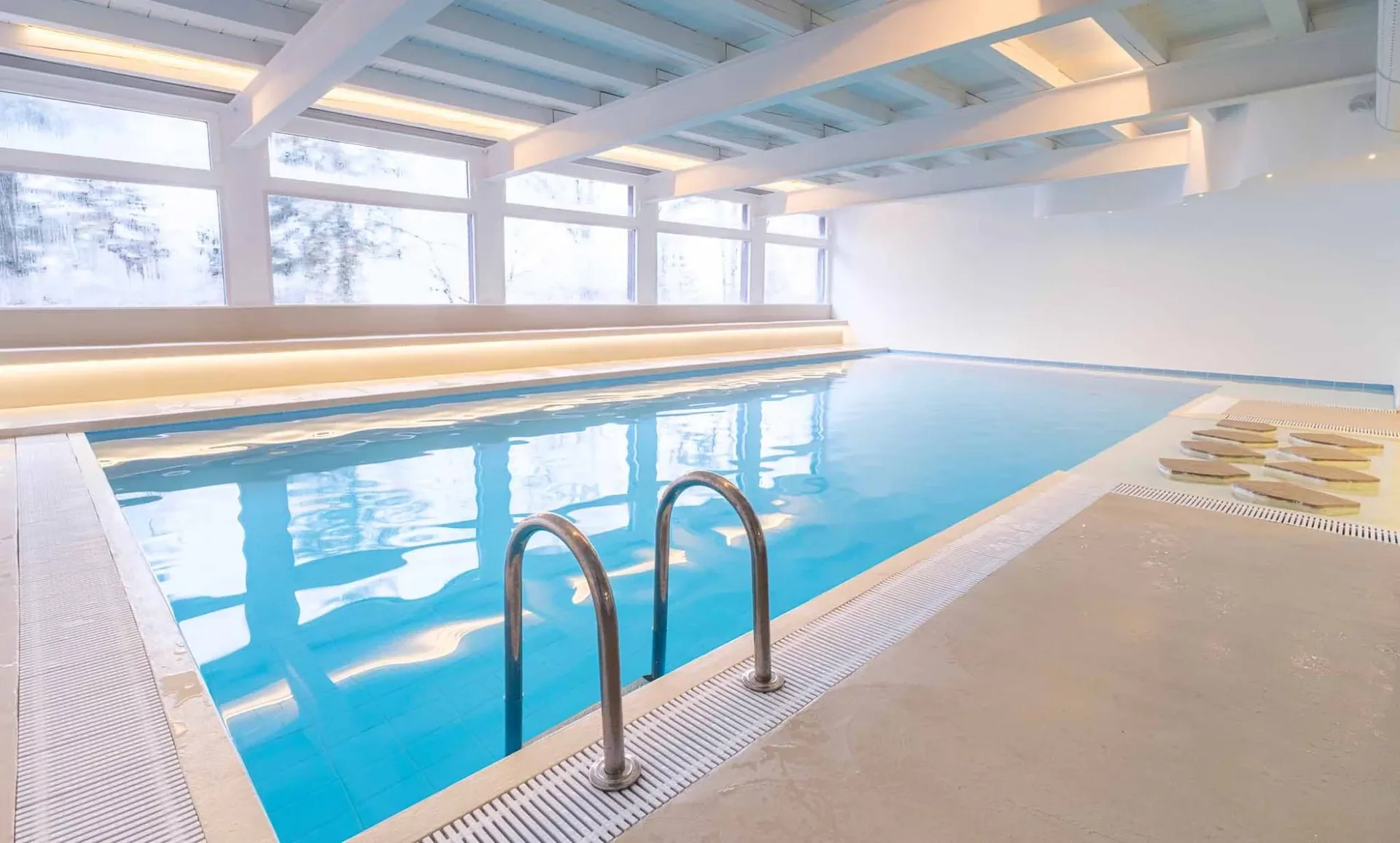 Piscina interna con scaletta e vetrate affacciate sul paesaggio innevato