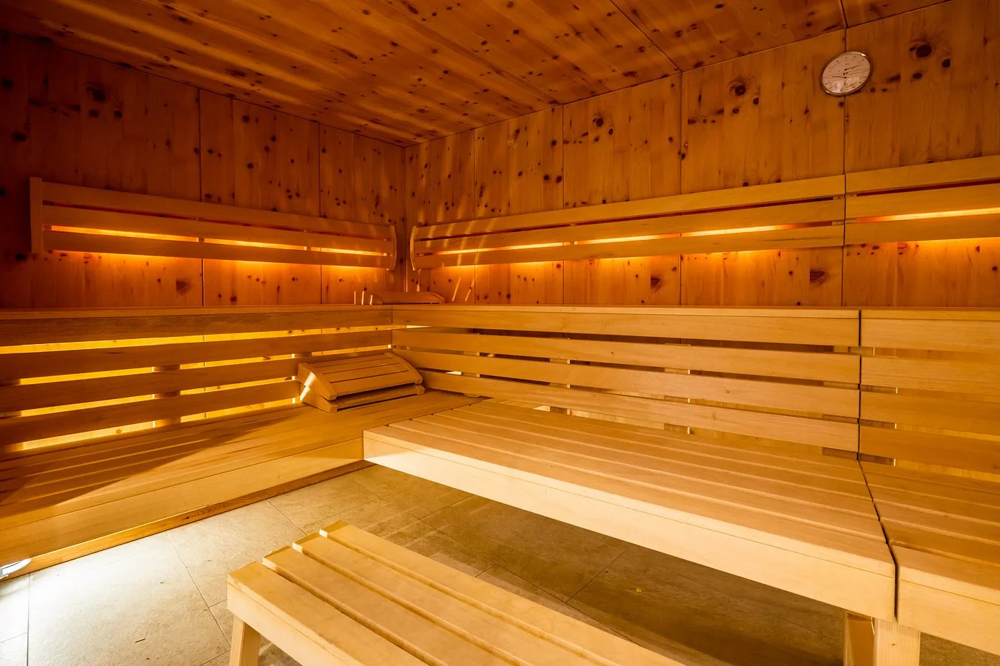 Interno della sauna finlandese in legno con illuminazione calda e panche