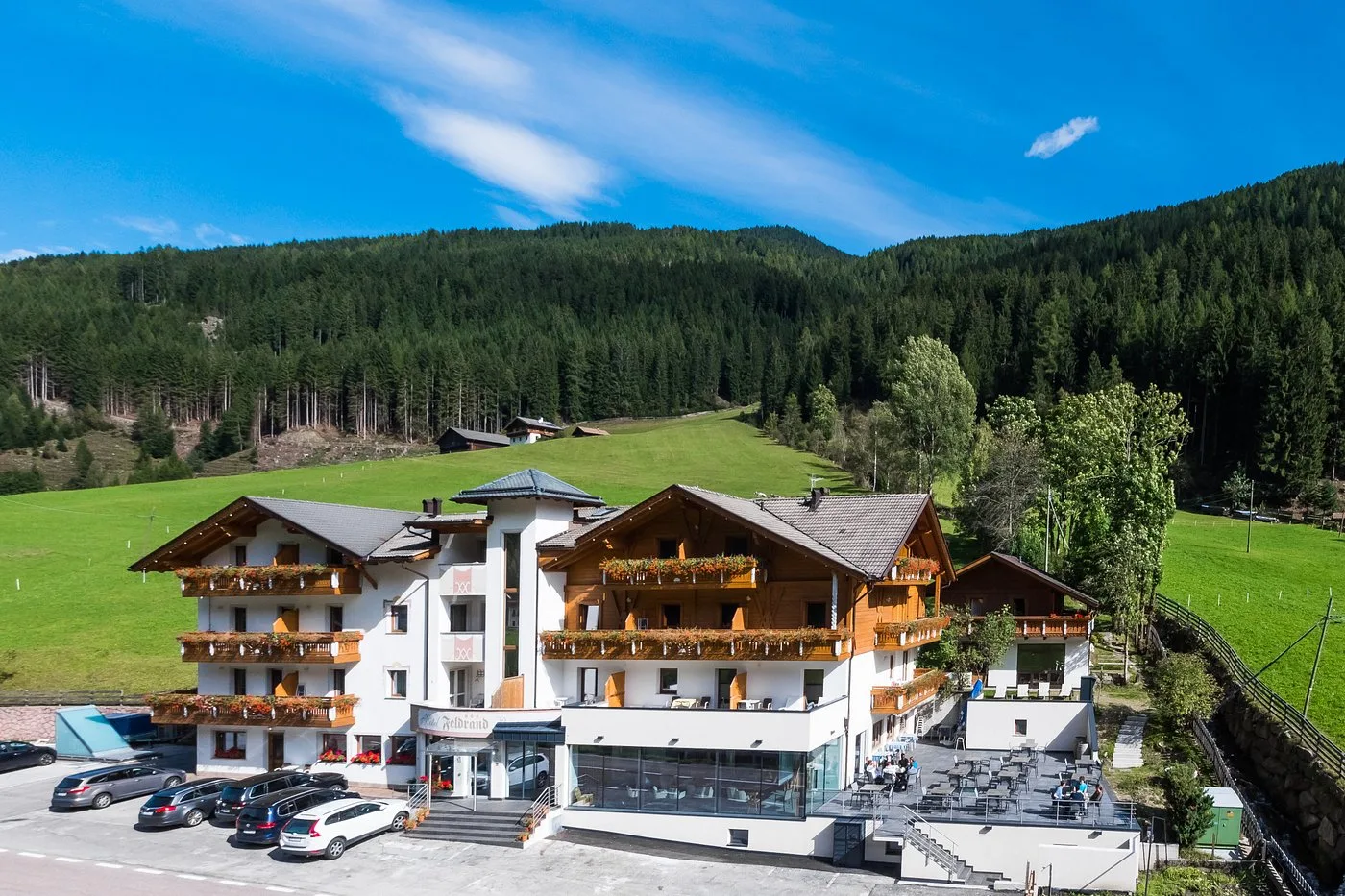 Vista aerea dell'Hotel Feldrand in estate con prati verdi e foresta alpina