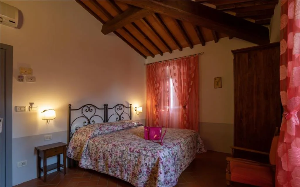 Camera matrimoniale con soffitto in travi di legno, letto in ferro battuto e tende rosse