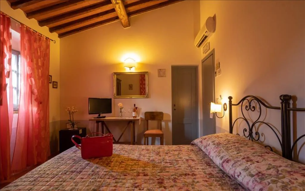 Camera da letto con travi a vista, scrivania, TV e tende rosa in stile rustico