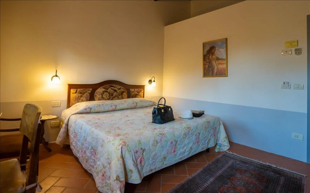 Camera da letto matrimoniale con testiera in legno, copriletto floreale e quadro decorativo
