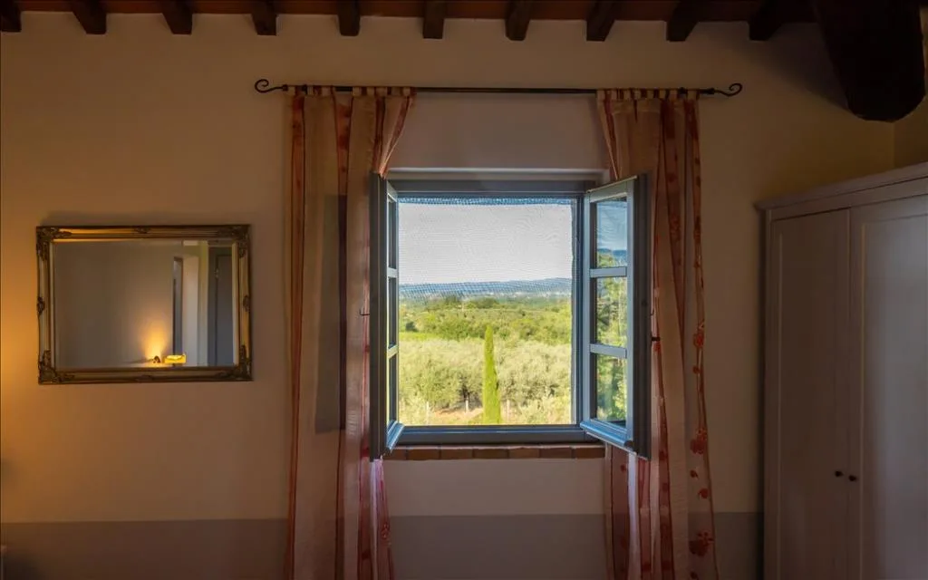 Finestra aperta con vista sulle colline e gli ulivi della campagna toscana