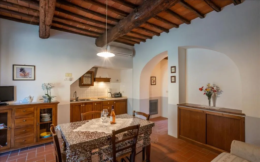 Cucina e zona pranzo rustica con travi a vista, tavolo apparecchiato e mobili in legno