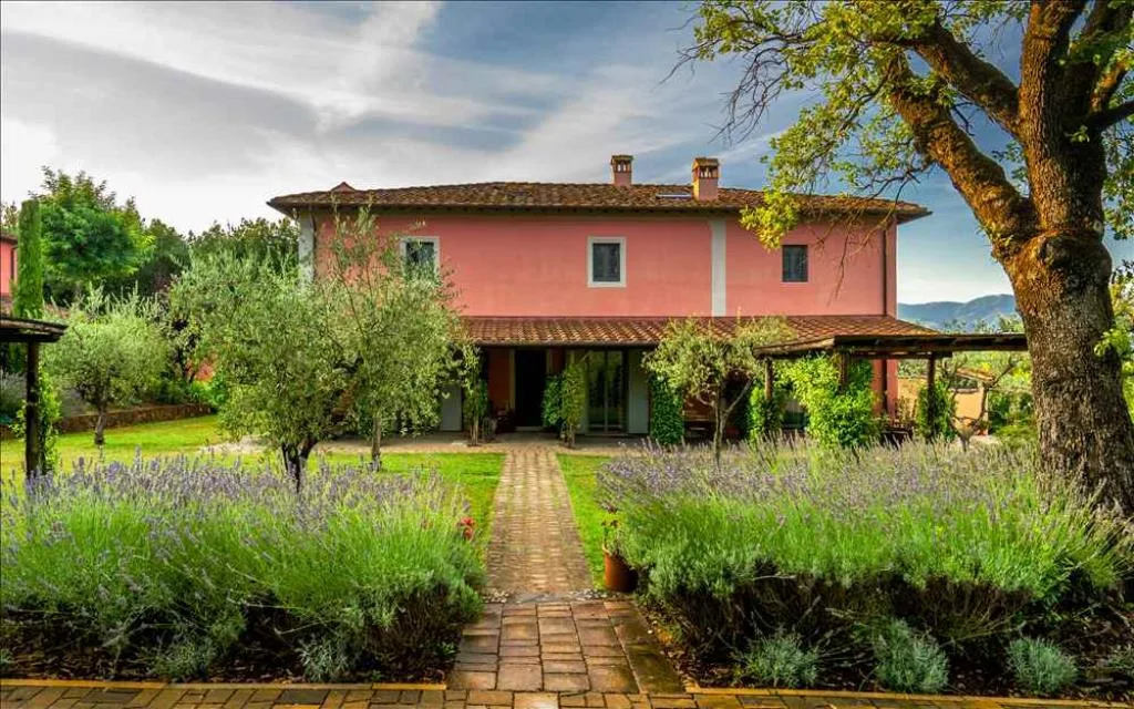Facciata posteriore della villa rosa con vialetto in mattoni, lavanda e pergolato