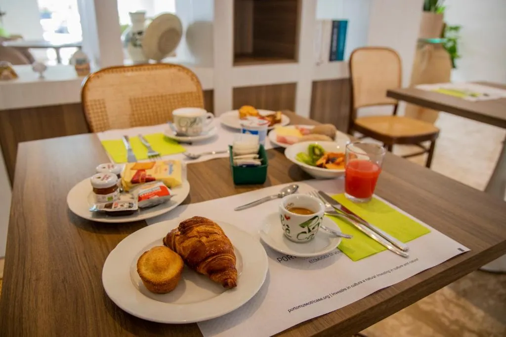 Tavolo della colazione con cornetto, caffè, succo, formaggi e frutta fresca