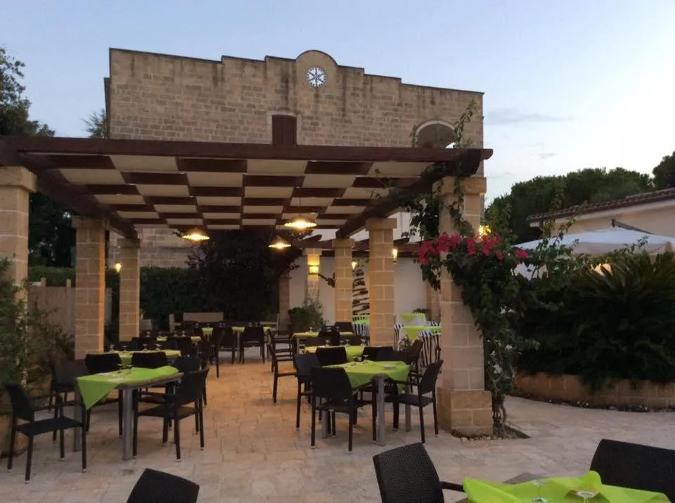 Ristorante esterno con pergolato, tavoli verdi e illuminazione serale