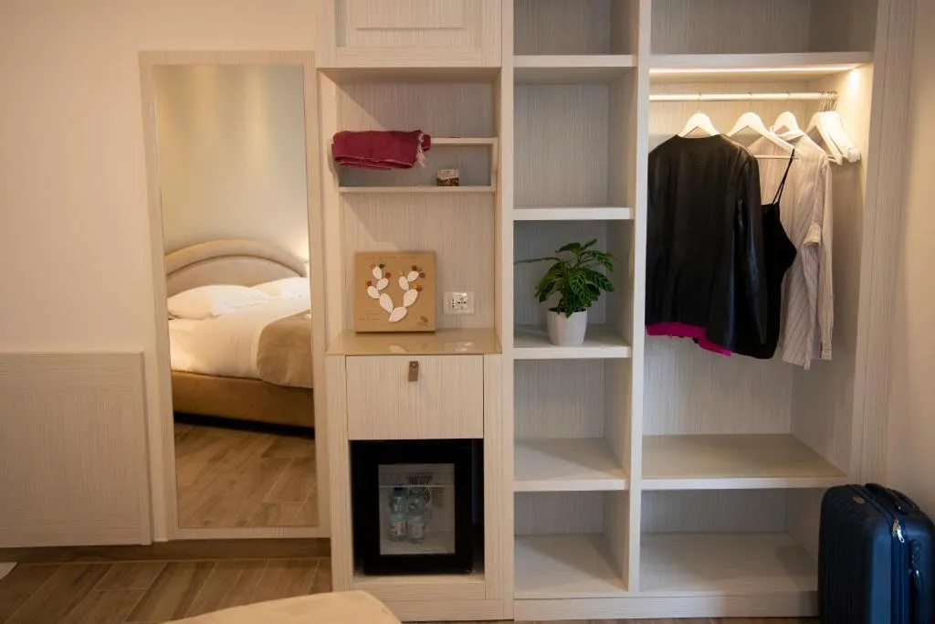 Dettaglio camera con armadio illuminato, specchio, minibar e vista sul letto