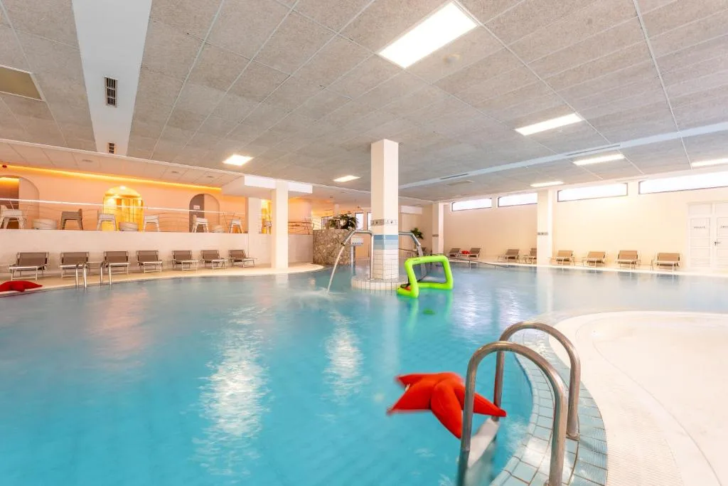 Piscina coperta con idromassaggio, lettini e giochi galleggianti colorati