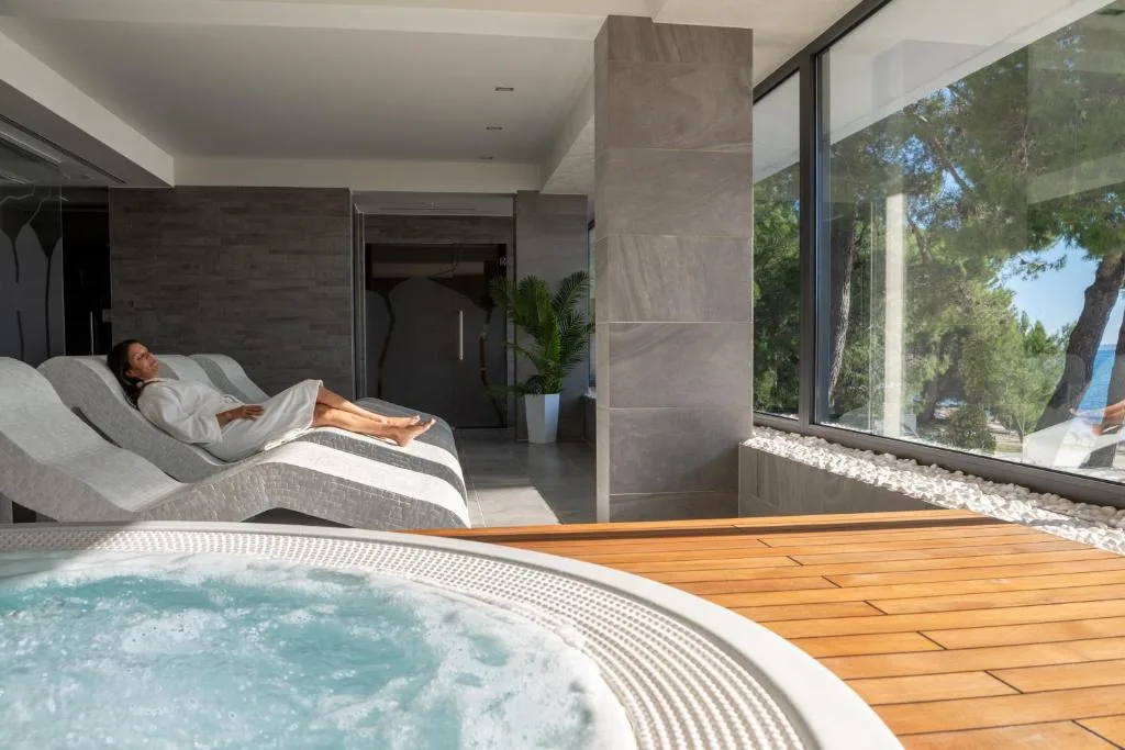Area spa con vasca idromassaggio, lettini relax e vista sul verde attraverso le vetrate