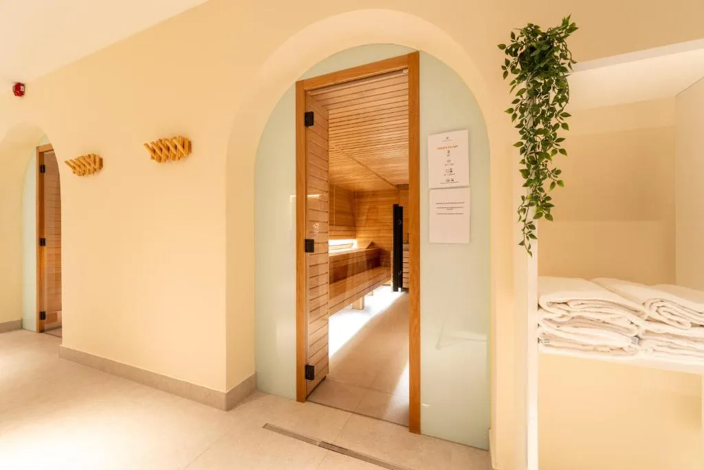 Ingresso della sauna in area benessere con archi, asciugamani e pianta verde