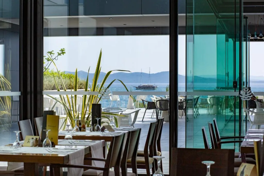 Sala ristorante con tavoli apparecchiati e vista sul mare attraverso le vetrate