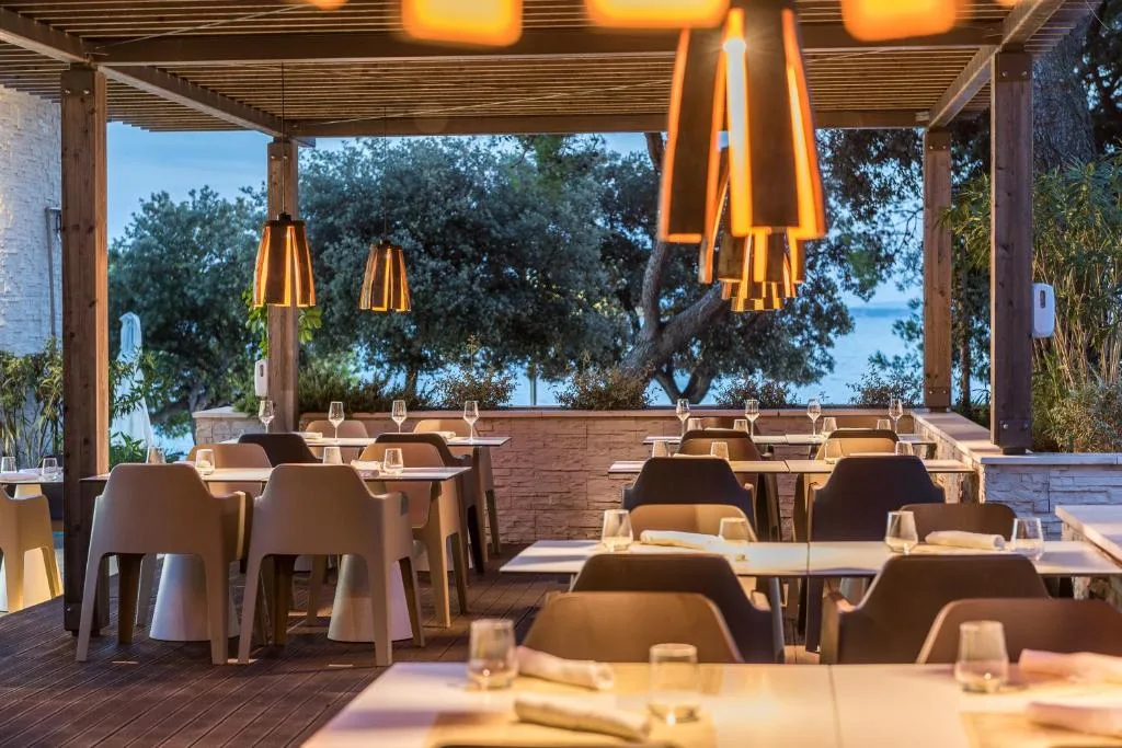 Terrazza ristorante con pergolato, tavoli apparecchiati e vista mare al tramonto