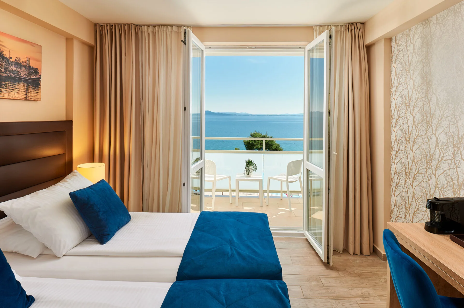 Camera con letto matrimoniale, cuscini blu e balcone con vista mare