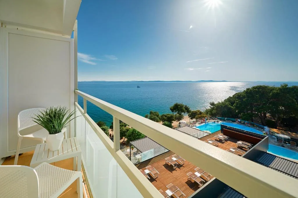 Balcone con sedie bianche e vista panoramica sul mare e la piscina dall'alto
