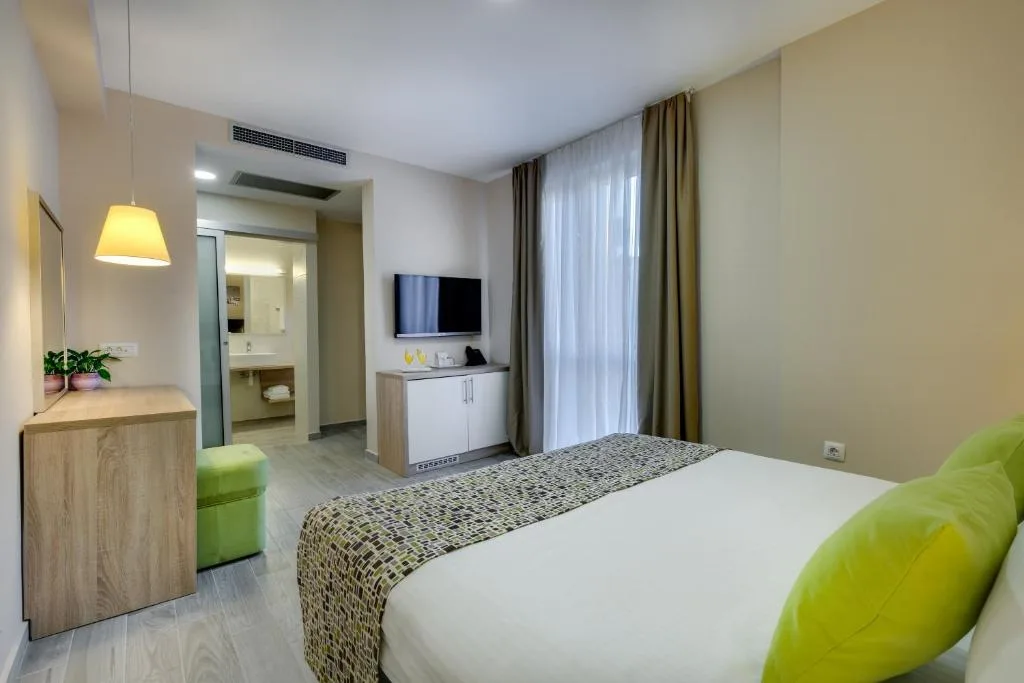 Camera moderna con letto, pouf verde, TV e bagno attiguo