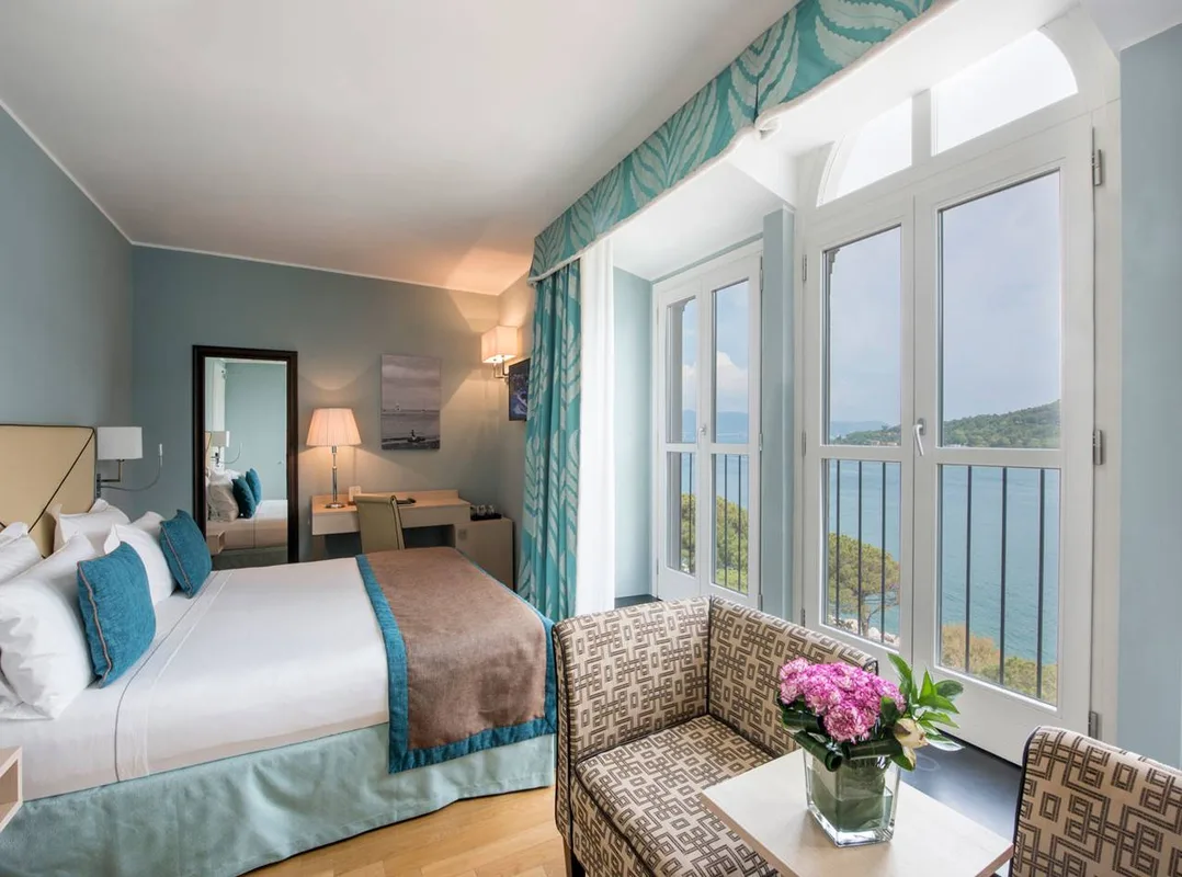 Elegante camera con letto matrimoniale e grandi finestre ad arco con vista sul mare