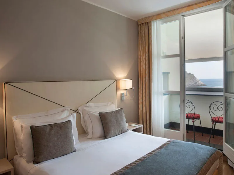 Camera con letto matrimoniale e balconcino affacciato sul promontorio e il mare