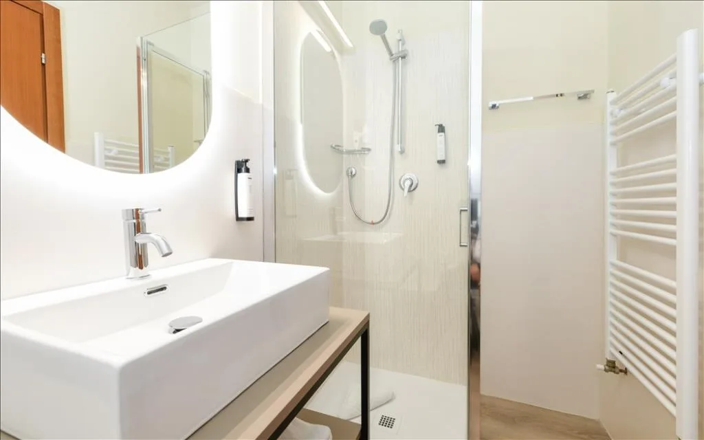 Bagno moderno con lavabo rettangolare, specchio illuminato e doccia con box in vetro