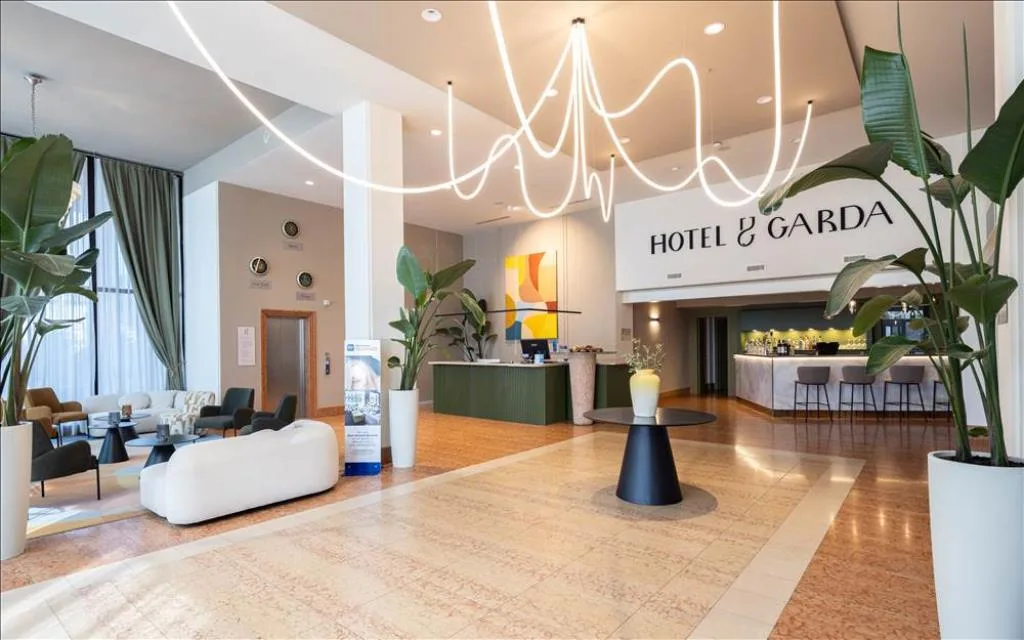 Hall dell'Hotel Garda con reception, area salotto, piante e lampadario di design